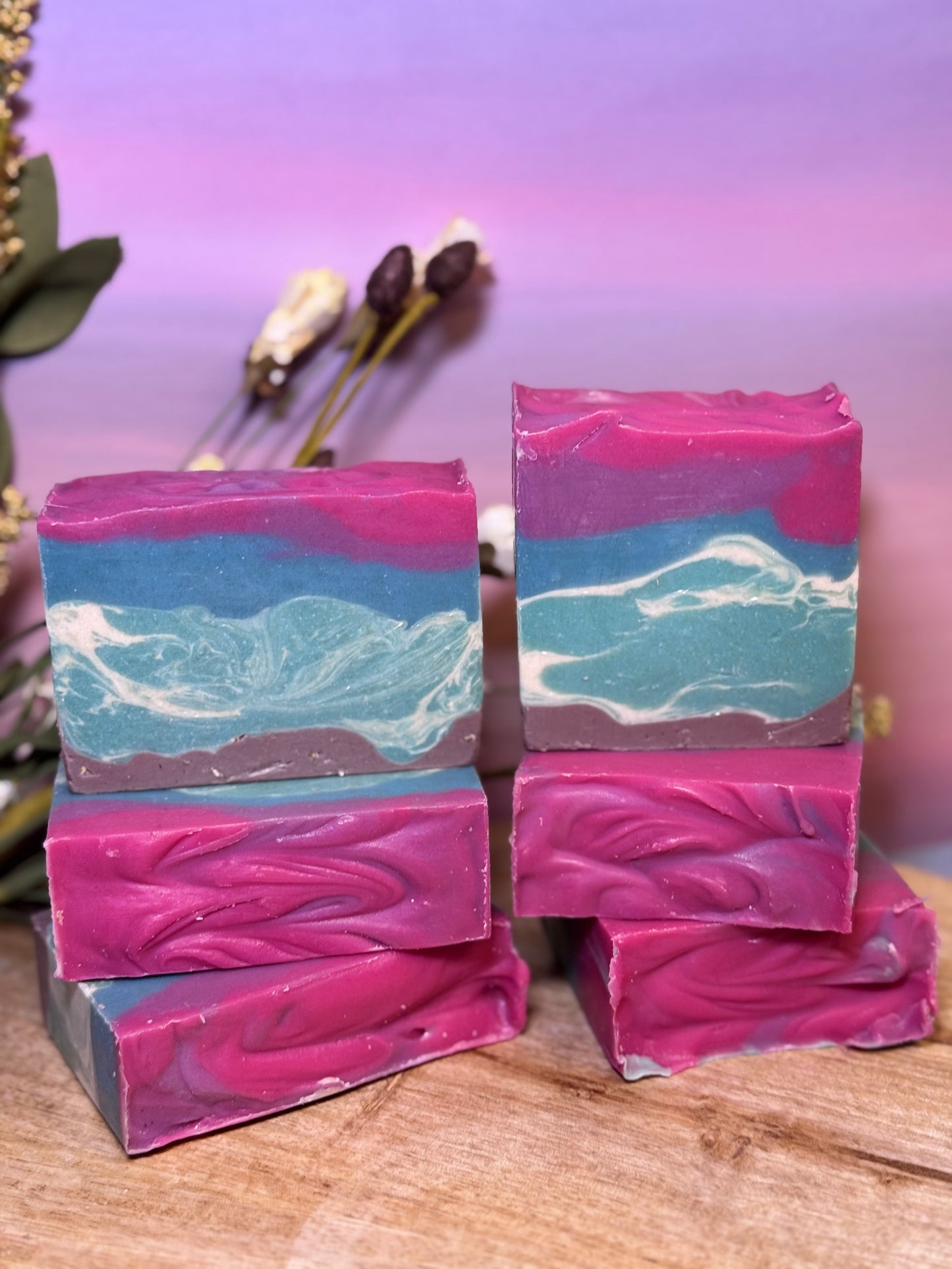 Stack of pink and blue marbled soap bars on a wooden surface with a blurred background