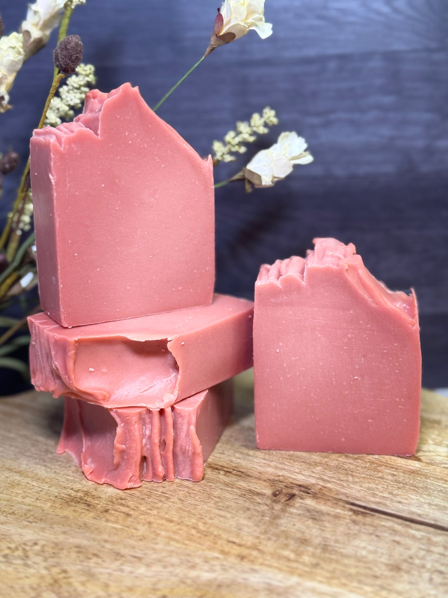 Four pink soap bars on a wooden surface with a dark background