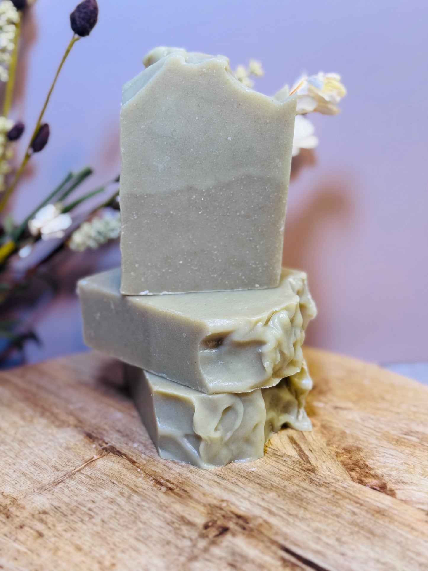 Three bars of soap on a decorative stand with a blurred natural background