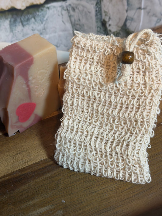 Natural loofah sponge on a wooden surface with a bar of soap in the background.