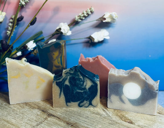 Handmade soap bars with artistic designs on a wooden surface with flowers in the background.