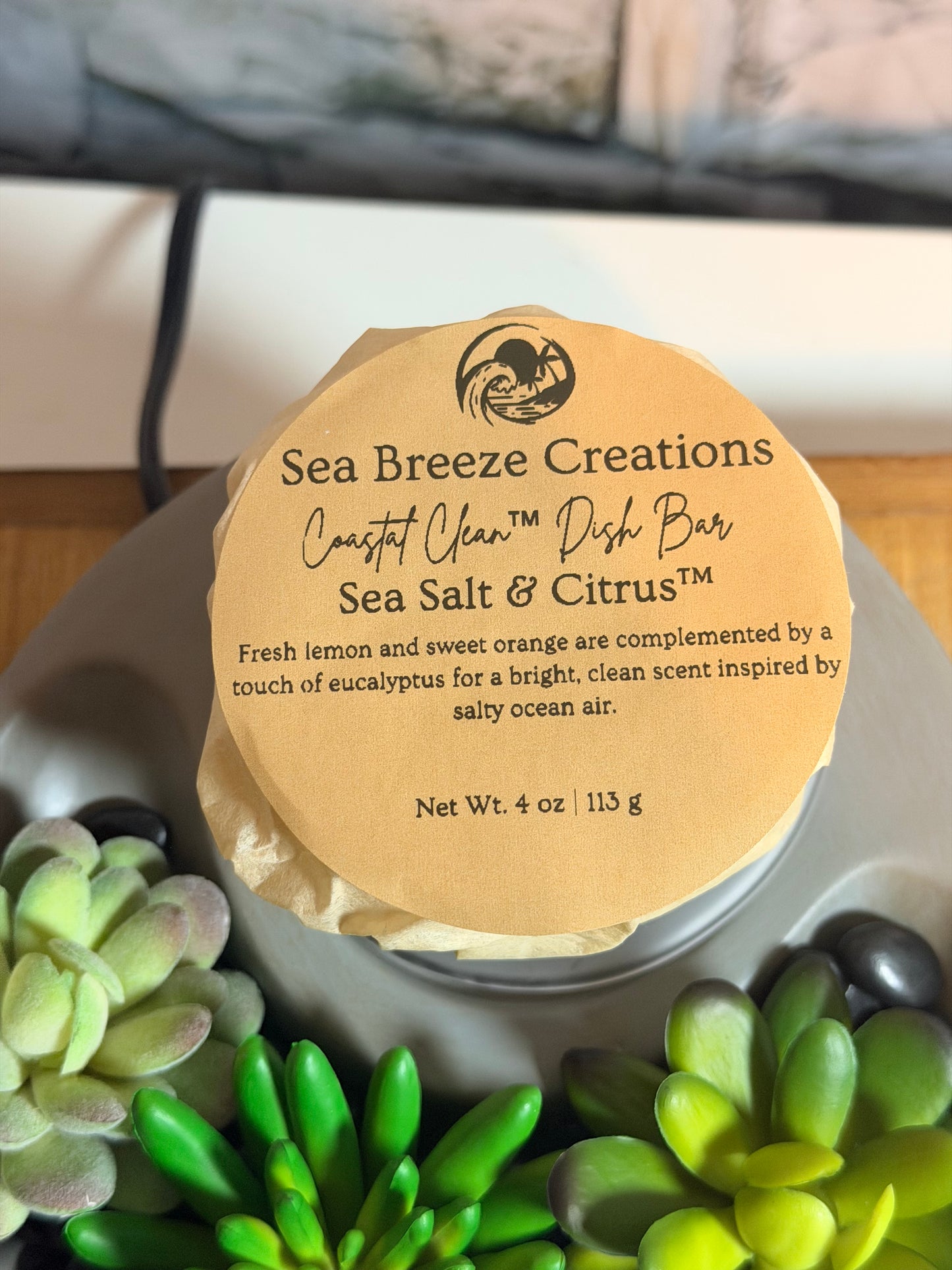 Sea Breeze Creations soap bar with a label on a surface with green plants.