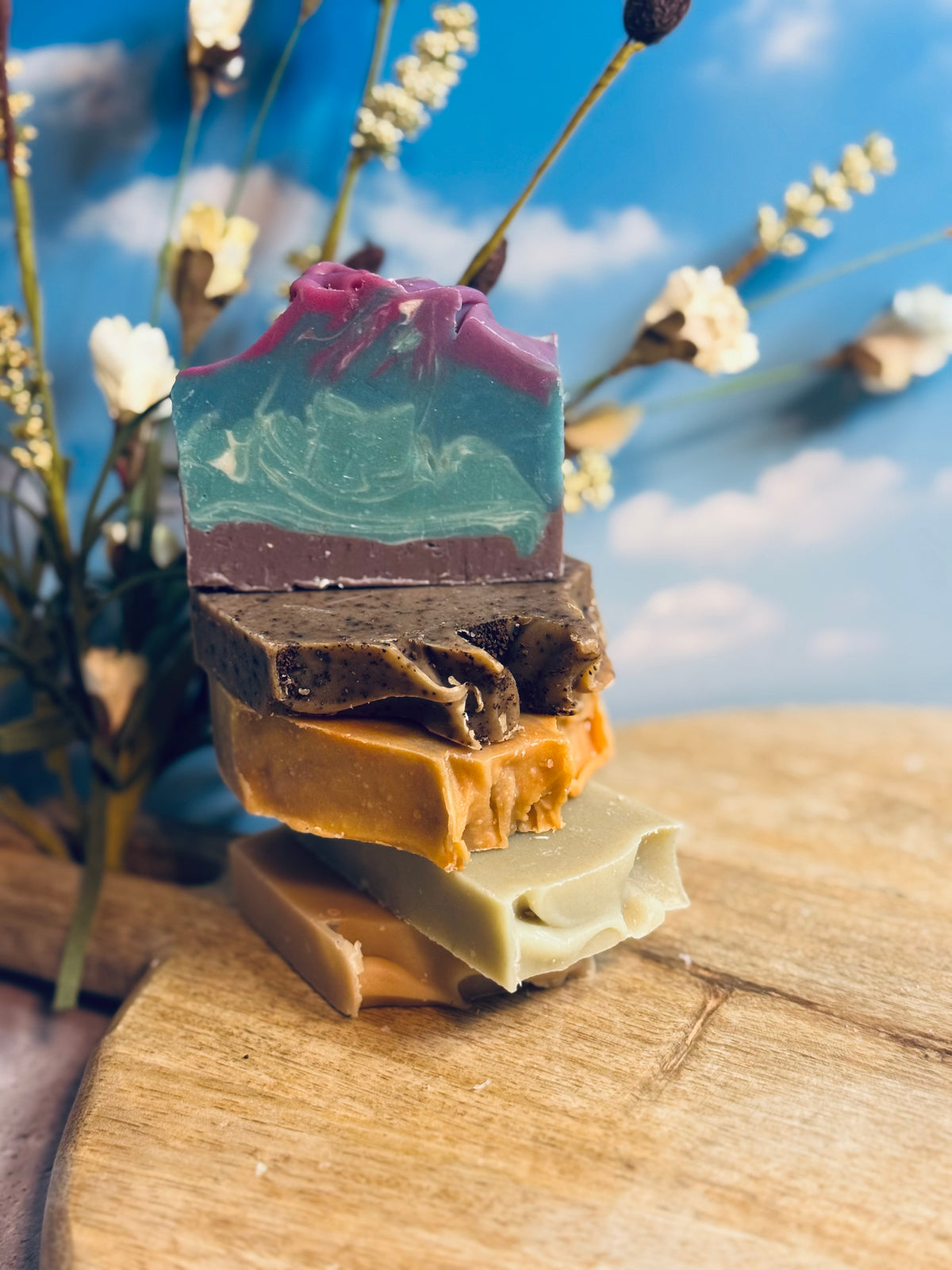 Stack of colorful soap bars on a wooden surface with a blurred natural background