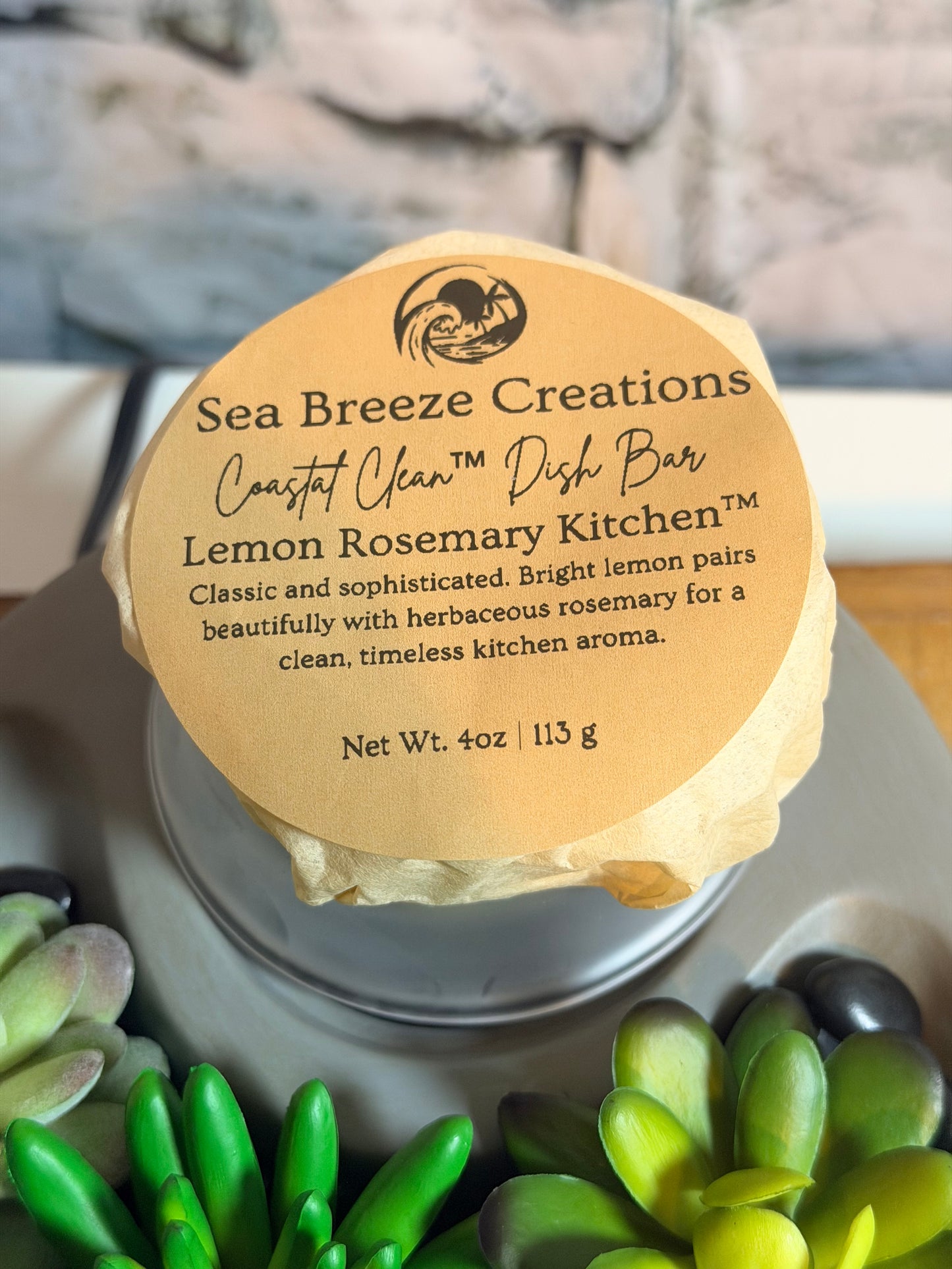 Bar of soap with a label on a stone surface with green plants.
