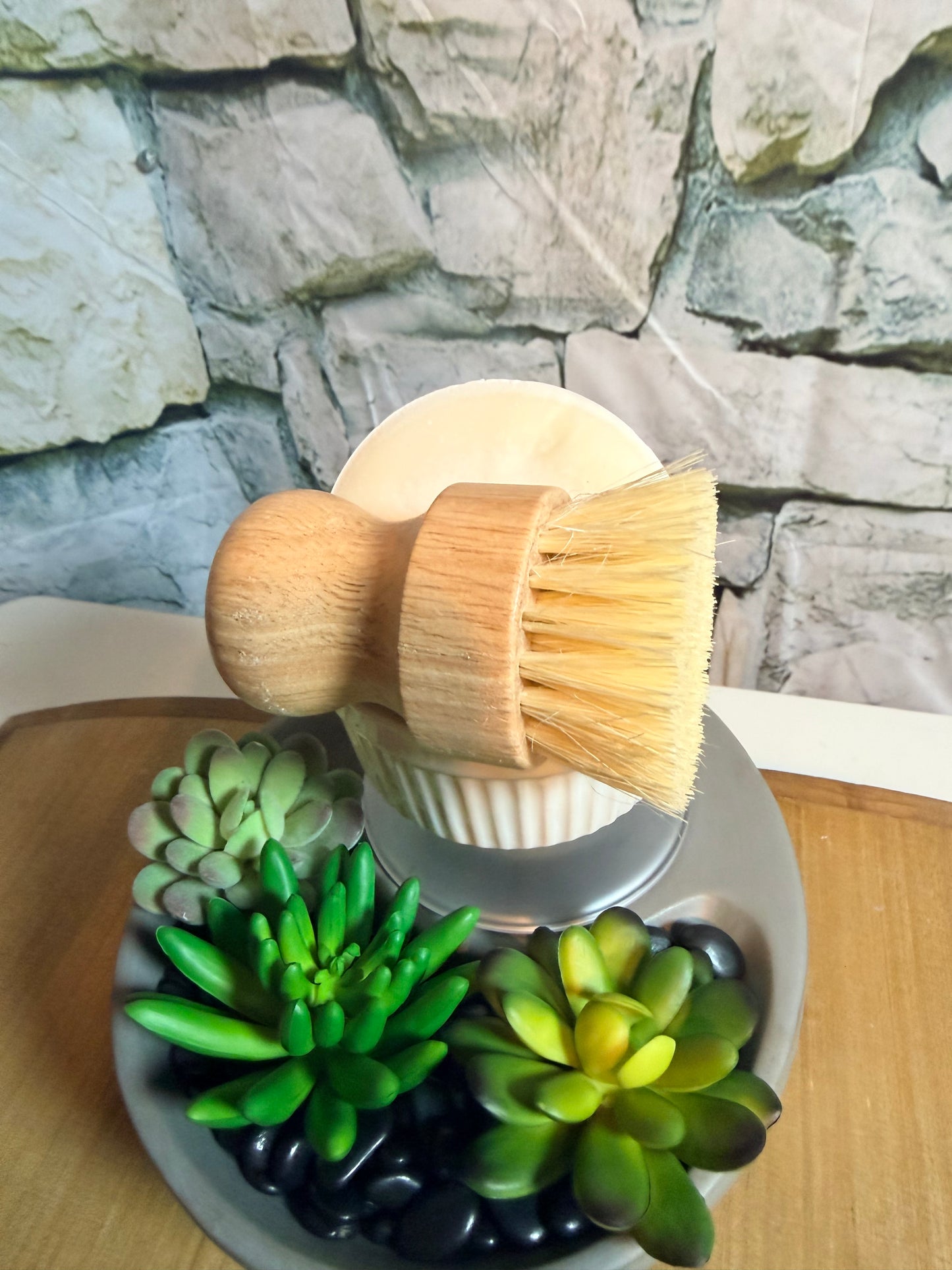 Wooden brush with a stone background and succulents in the foreground