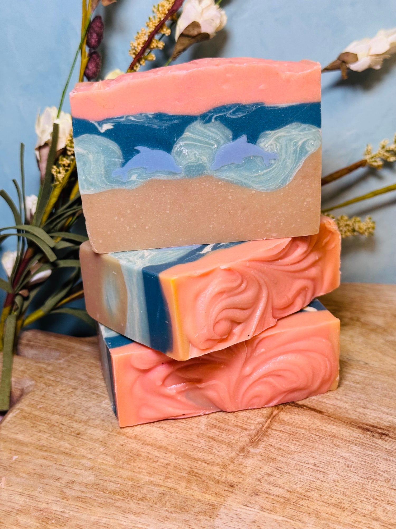 Stack of three soap bars with ocean and dolphin design on a wooden surface