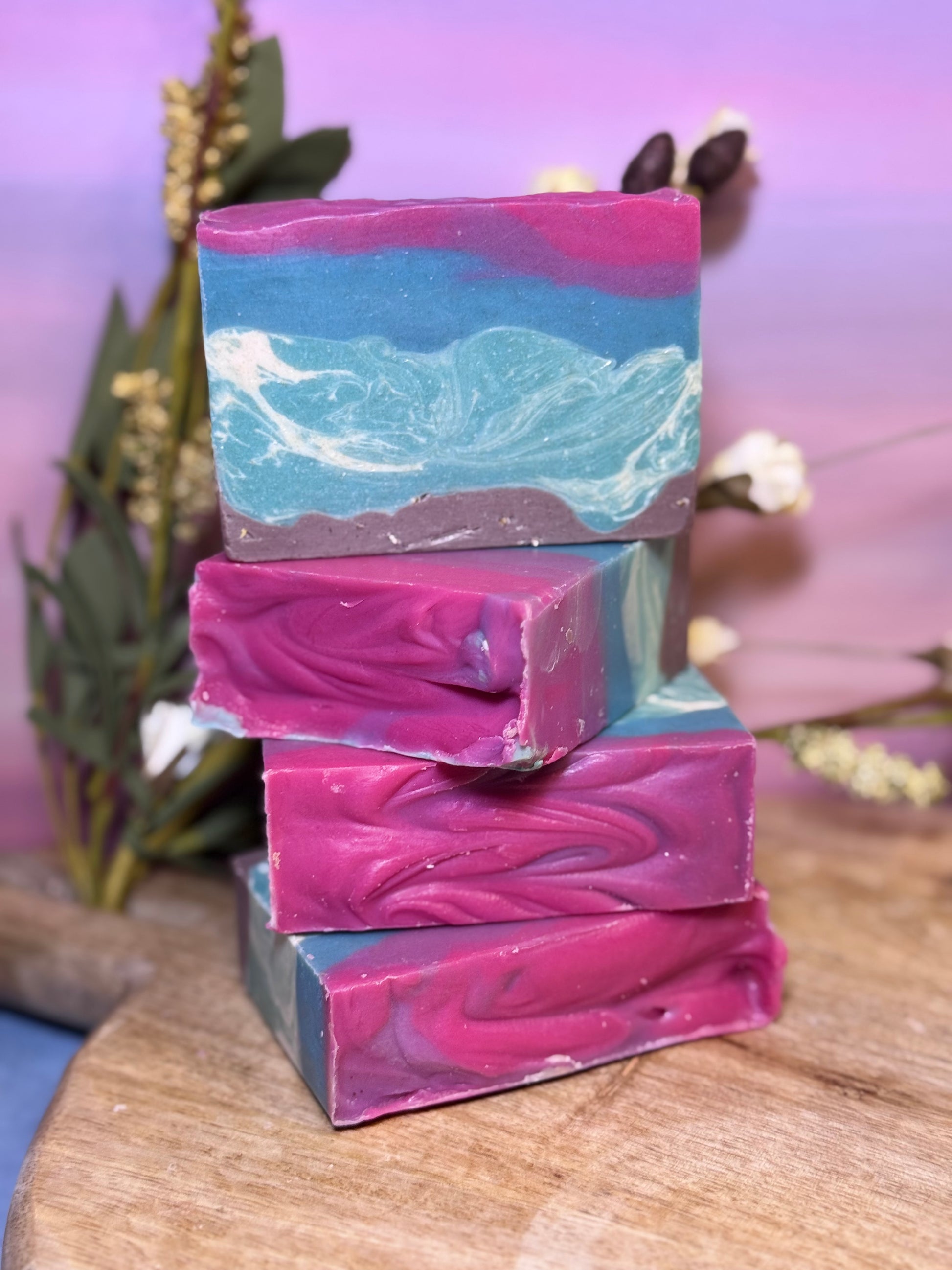 Stack of colorful soap bars with a swirled pattern on a wooden surface.