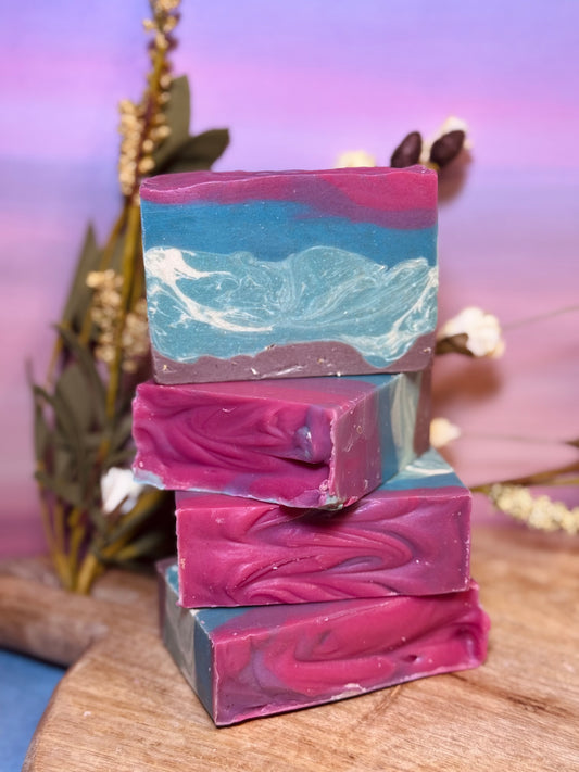 Stack of colorful soap bars on a wooden surface with a blurred natural background