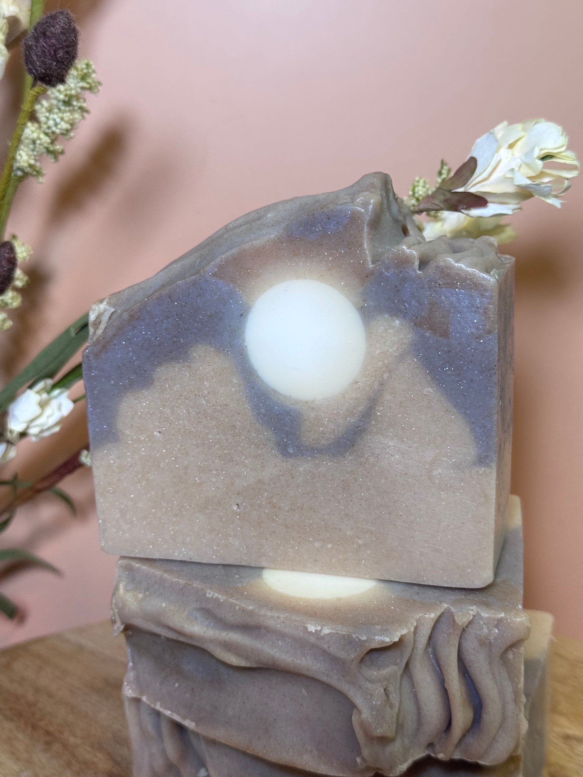 Decorative soap bar with floral elements on a soft pink background