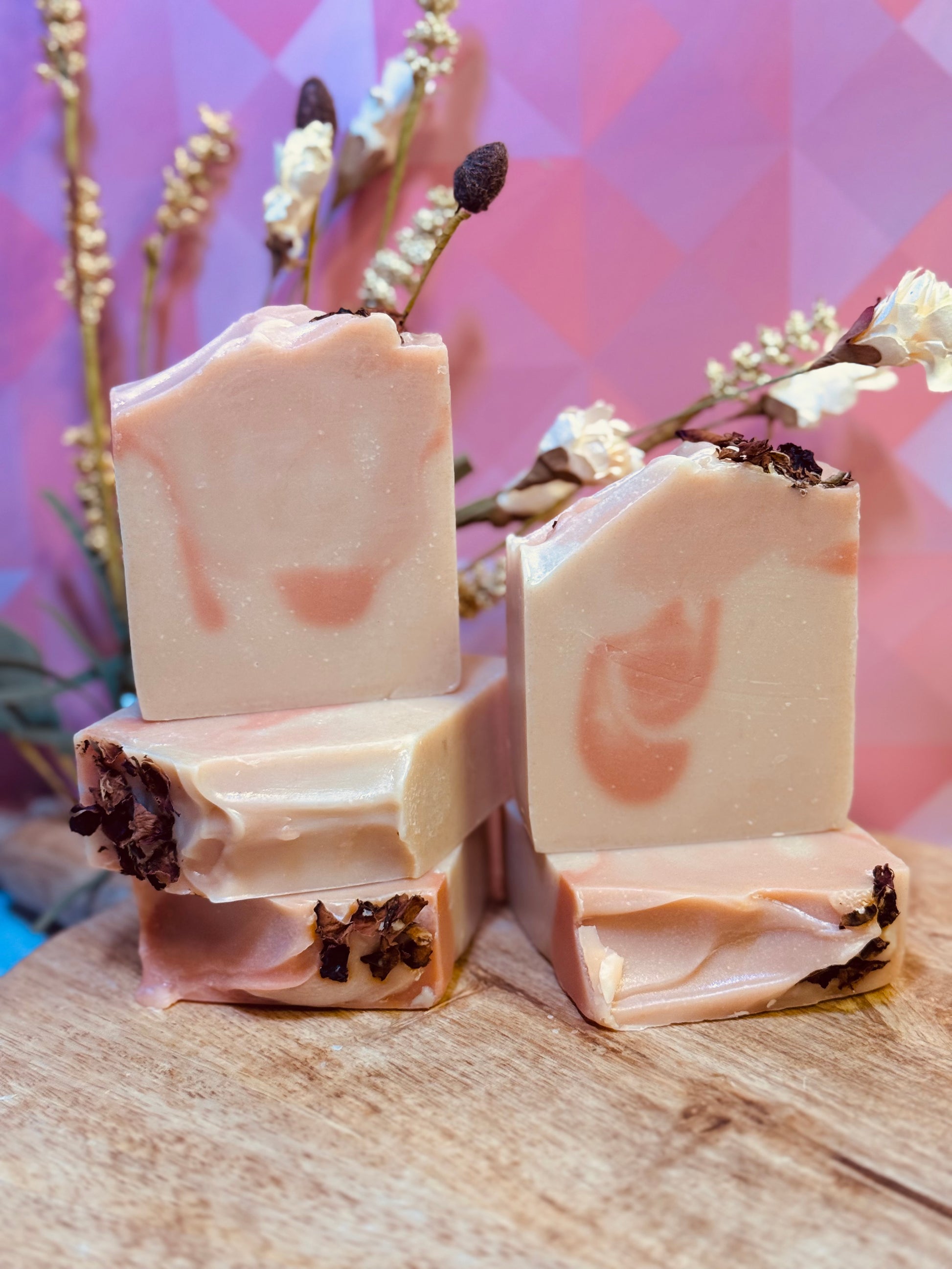 five bars of soap with natural elements on a wooden surface and floral  background