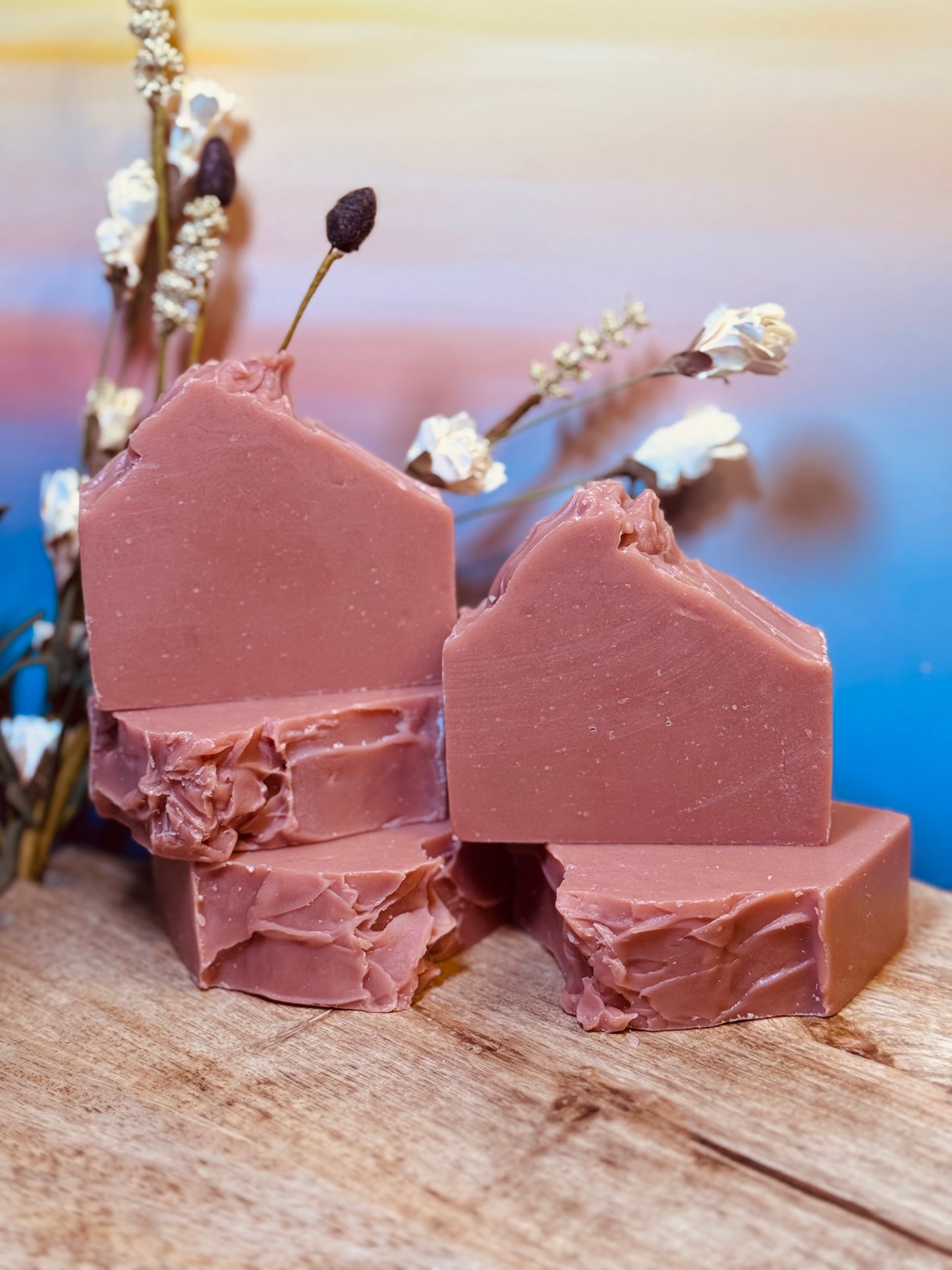 Pink soap bars on a wooden surface with a blurred natural background